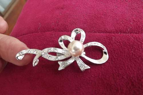 Silver toned brooch in bow shape with tiny stones and pearl.New condition