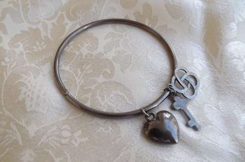 Pretty antique colour metal bangle with 3 charms.New condition