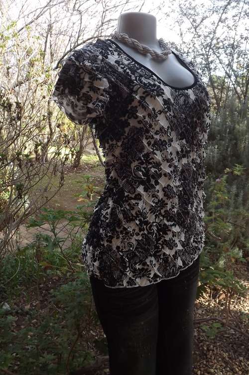 Black and white floral capped sleeve top with small diagonal frills.Size 38/14.Rounded neckline.