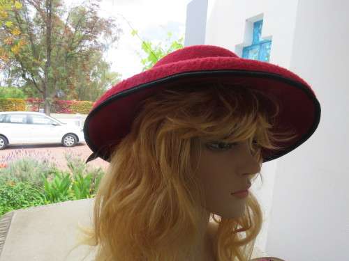 Red hard hat with brim bended down wards.Black band and bow with red fabric flower.Good condition