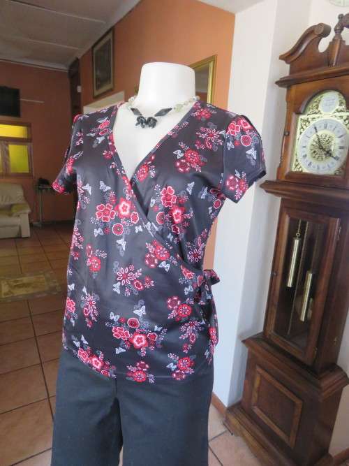 Crossover black silky 100% polyester top with cheerful red floral pattern.Size 36/12.Capped sleeves