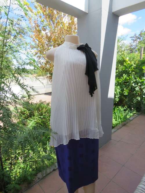 White permanent pleated top with high collar opening at back.Closing with 2 buttons.Size 40/16