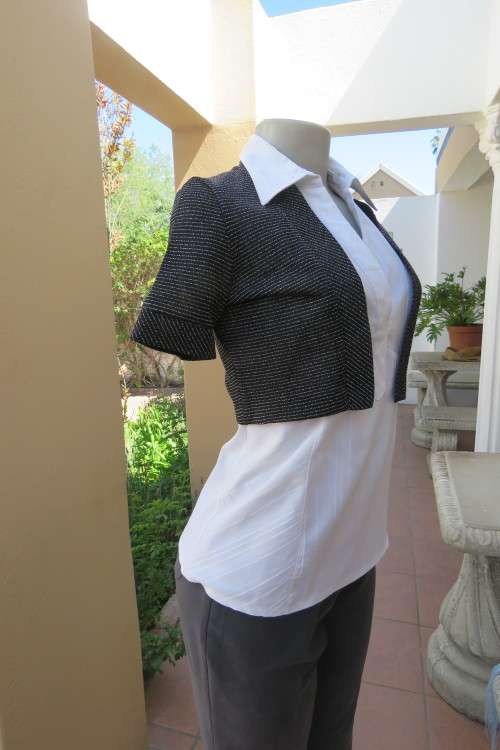 Pretty short sleeve black open bolero with horizontal silver lurex thread. Size 32/8.