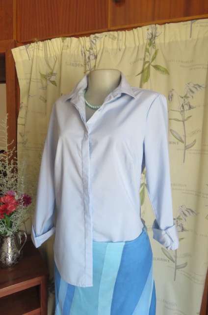 Styled powder blue long sleeve top by 'Fix'in size 36/12. Hidden button down front with shirt collar