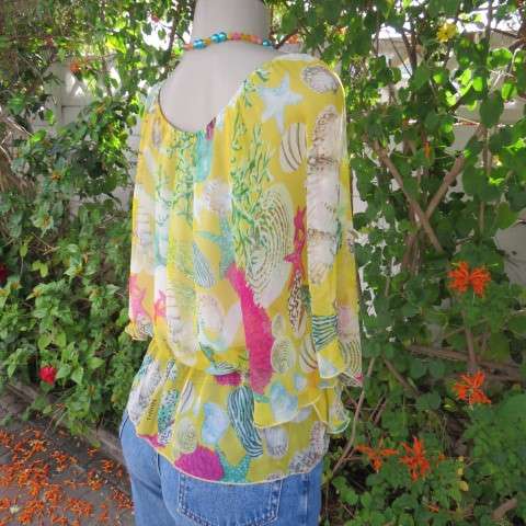 Sheer polyester peplum style top in yellow with pink and green shell designs. Size 38/14.
