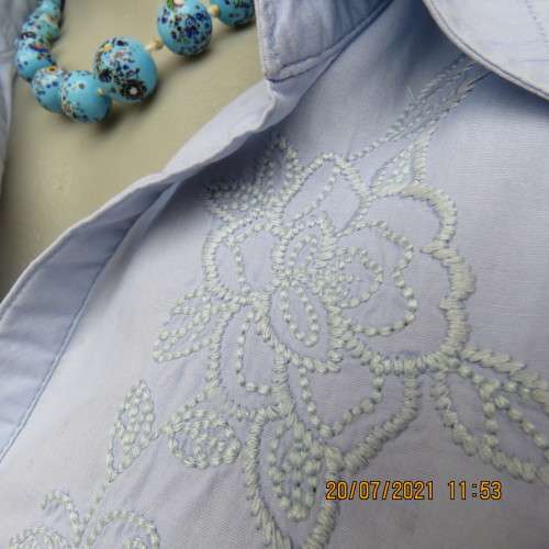 High quality powder blue button down top with tasteful floral front embroidery. Size 38 to 40.By M H