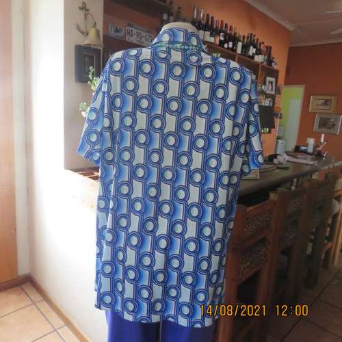 Geometric printed short sleeve top in blue shades with green accents. By DAVLEY size 46/22.As new