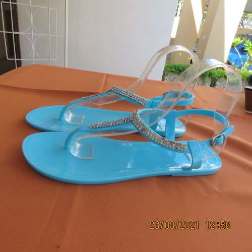 Pair of blue plastic sandals in size 7. Strap between toes and around ankle.Faux diamond decoration.