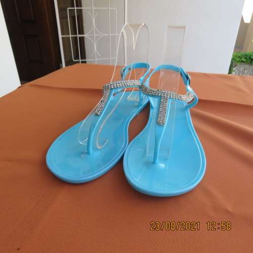 Pair of blue plastic sandals in size 7. Strap between toes and around ankle.Faux diamond decoration.