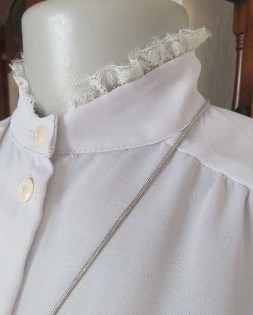 Stylish 80`s long sleeve button down light grey blouse with high banded collar.Size 32 by FOSHINI.