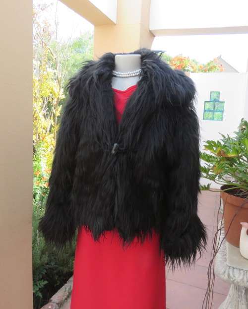 Black faux fur hip length jacket with open rounded collar.Close with long button and loop.Size 38/40