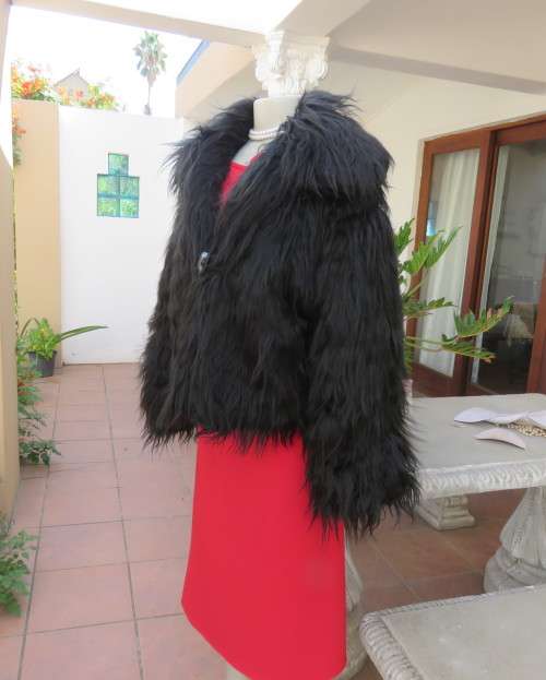 Black faux fur hip length jacket with open rounded collar.Close with long button and loop.Size 38/40