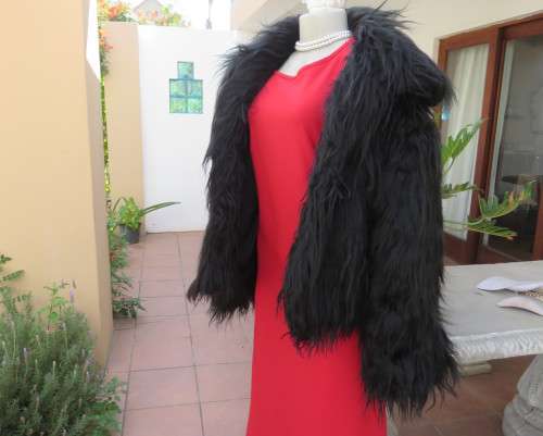 Black faux fur hip length jacket with open rounded collar.Close with long button and loop.Size 38/40