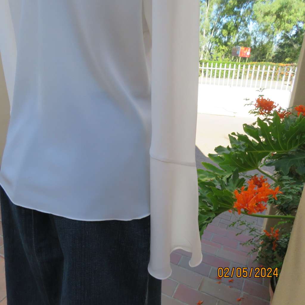 Pretty white polyester slip over top with long sleeves/flare cuffs. Front braided opening.Size 38/40