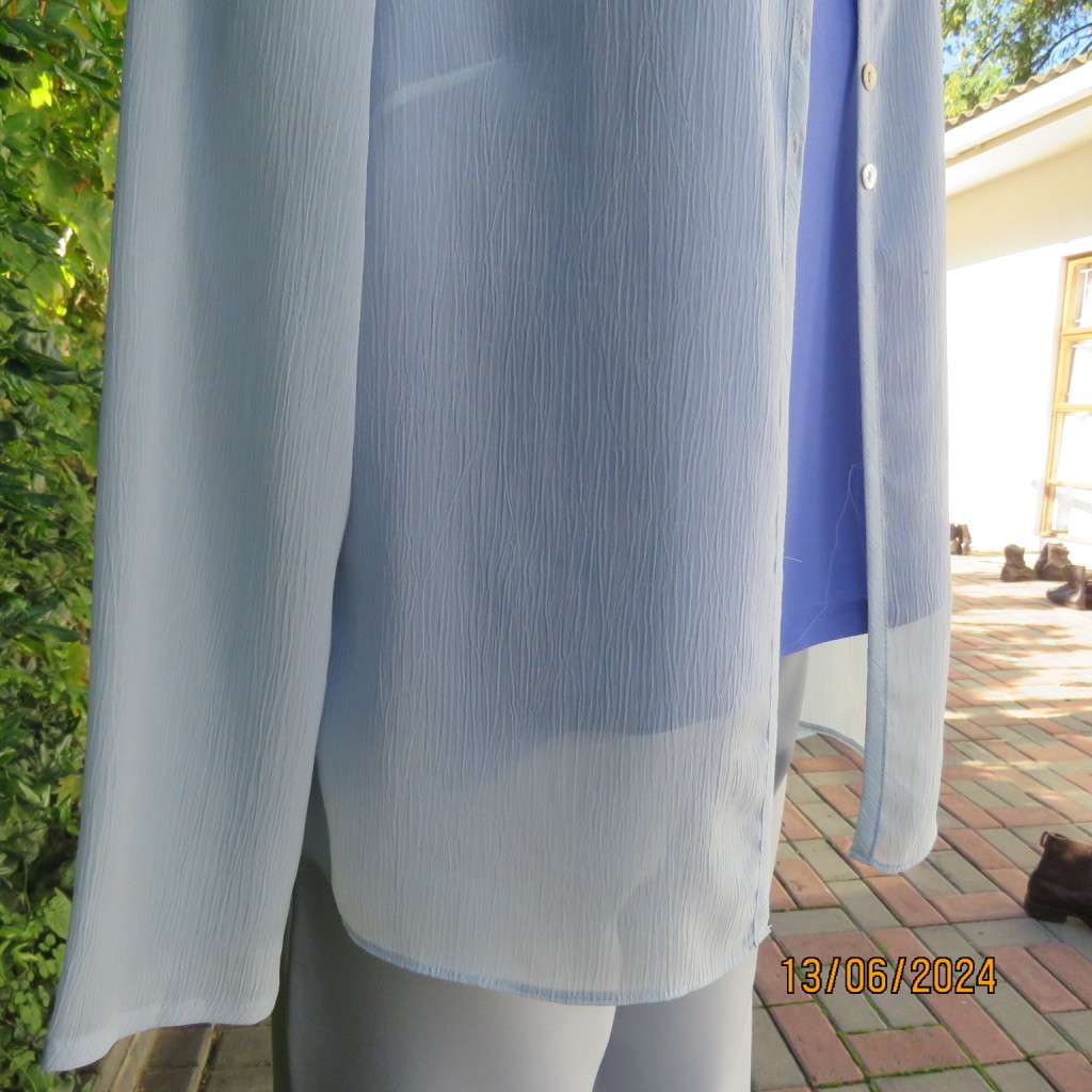 Dainty powder blue long sleeve cover-up in crinkled polyester. 3 tiny button closure.Size 38. As new