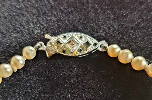 ANTIQUE FAUX SINGLE STRING PEARL BEADED NECKLACE WITH ORNATE CLASP.