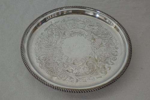 AN EXQUISITE VINTAGE SILVER PLATED ROUND FOOTED SERVING TRAY WITH STUNNING ORNATE ENGRAVED DETAILING