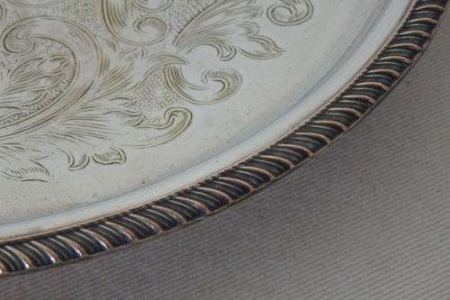 AN EXQUISITE VINTAGE SILVER PLATED ROUND FOOTED SERVING TRAY WITH STUNNING ORNATE ENGRAVED DETAILING