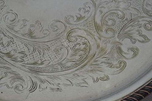 AN EXQUISITE VINTAGE SILVER PLATED ROUND FOOTED SERVING TRAY WITH STUNNING ORNATE ENGRAVED DETAILING
