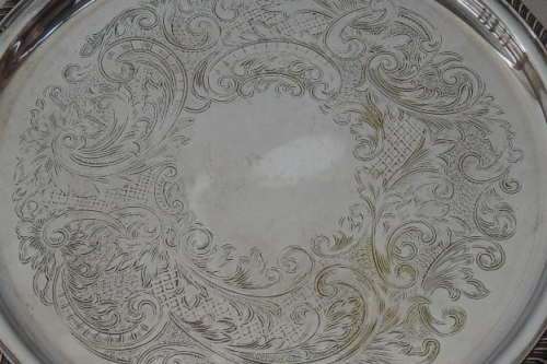 AN EXQUISITE VINTAGE SILVER PLATED ROUND FOOTED SERVING TRAY WITH STUNNING ORNATE ENGRAVED DETAILING
