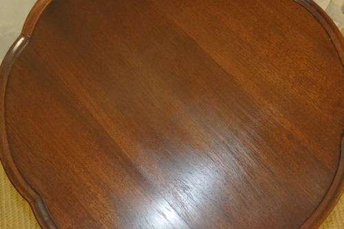 A MAGNIFICENT TEAK OCCASIONAL TABLE WITH BROAD RIMMED DETAILED TOP AND THREE BRASS TOE CAPS