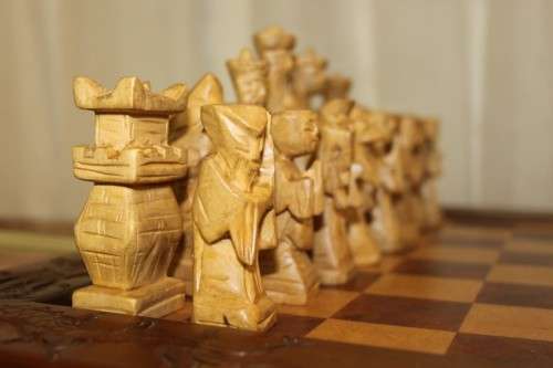 A SUPERB VINTAGE HAND-CARVED ORIENTAL FOLDING CHESS BOARD AND CARVED CHESS SET IN AWESOME CONDITION