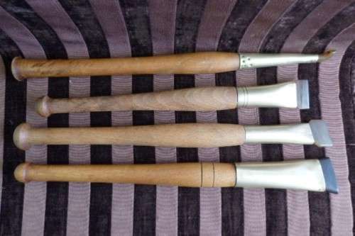 An incredible set of four vintage sculpting tools with wooden handles, brass cuffs & celluloid tips