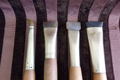 An incredible set of four vintage sculpting tools with wooden handles, brass cuffs & celluloid tips