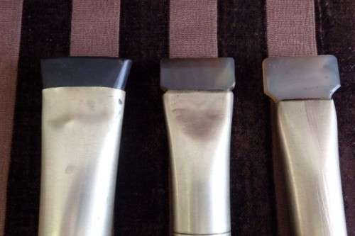 An incredible set of four vintage sculpting tools with wooden handles, brass cuffs & celluloid tips