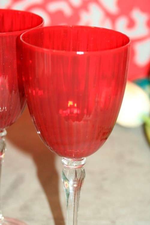 A stylish and modern boxed set of 4x tall wine glasses in a deep red colour with clear glass stems