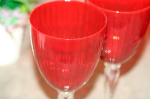 A stylish and modern boxed set of 4x tall wine glasses in a deep red colour with clear glass stems