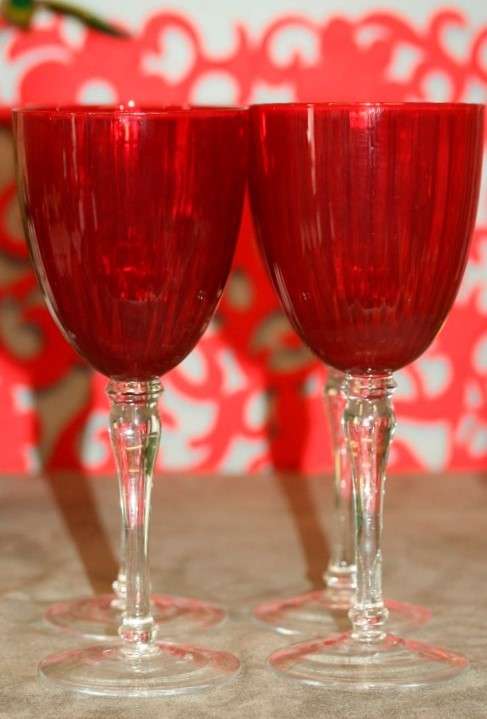 A stylish and modern boxed set of 4x tall wine glasses in a deep red colour with clear glass stems