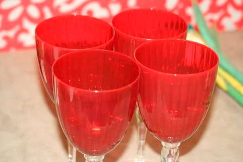 A stylish and modern boxed set of 4x tall wine glasses in a deep red colour with clear glass stems