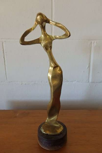 A beautiful tall ornamental brass abstract figurine on a wooden stand in wonderful condition