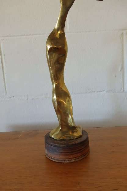 A beautiful tall ornamental brass abstract figurine on a wooden stand in wonderful condition