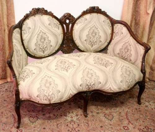 An exquisite antique Victorian carved settee with stylish new upholstery.