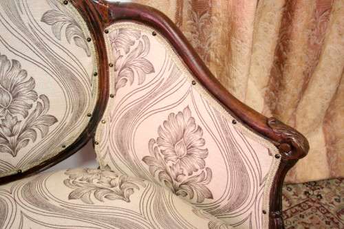 An exquisite antique Victorian carved settee with stylish new upholstery.