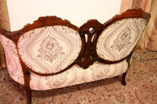 An exquisite antique Victorian carved settee with stylish new upholstery.