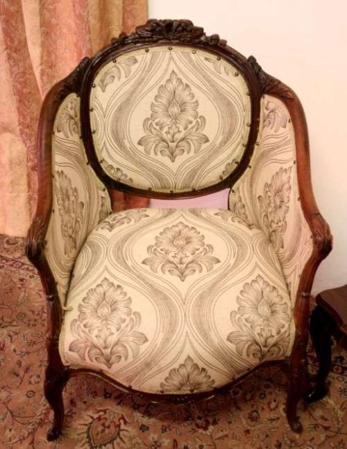 An elegant hand carved Victorian arm chair with gorgeous new fabric.