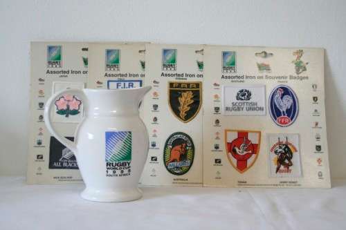 An awesome "1995 Rugby World Cup" commemorative jug and 16 iron on badges on display cards