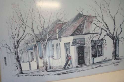 **RS17** A beautiful signed "Ted Hoefsloot" print framed behind glass of a scene of houses.