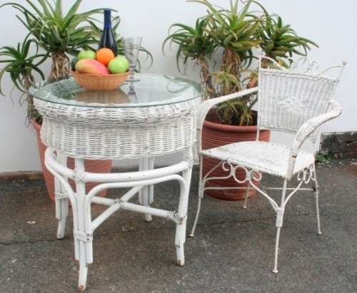 A gorgeous white painted wicker "all weather" outdoor/ patio table with a glass top and a chair