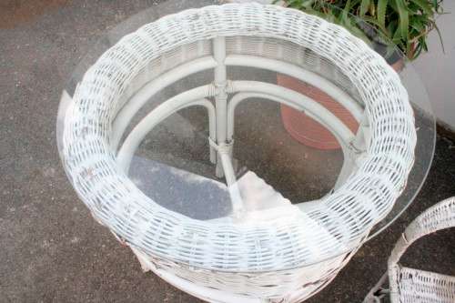 A gorgeous white painted wicker "all weather" outdoor/ patio table with a glass top and a chair