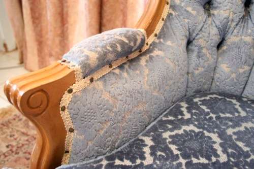 2 beautiful, elegant carved Victorian sofas with deep button detailing and blue period style fabric.