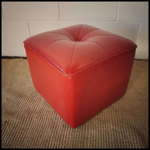 A beautiful, comfy red ottoman with a leather-like upholstery - perfect addition to a living room