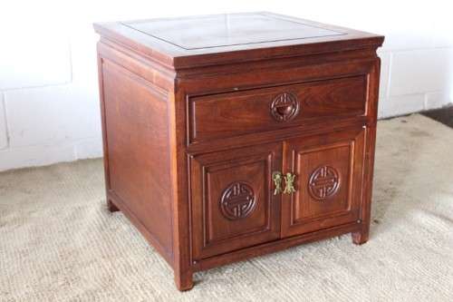 A beautifully carved oriental Elm wood "end" cupboard with brass symbol handles and a drawer