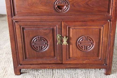 A beautifully carved oriental Elm wood "end" cupboard with brass symbol handles and a drawer