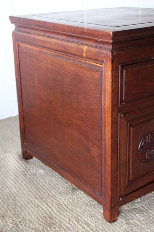 A beautifully carved oriental Elm wood "end" cupboard with brass symbol handles and a drawer