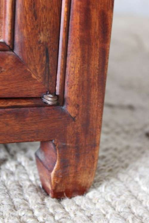 A beautifully carved oriental Elm wood "end" cupboard with brass symbol handles and a drawer