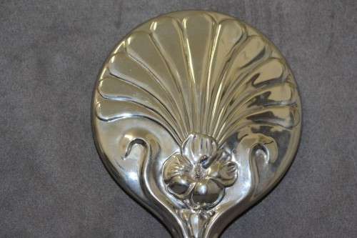 A beautiful, vintage ladies round chrome hand held vanity mirror with flower detailing on the back.